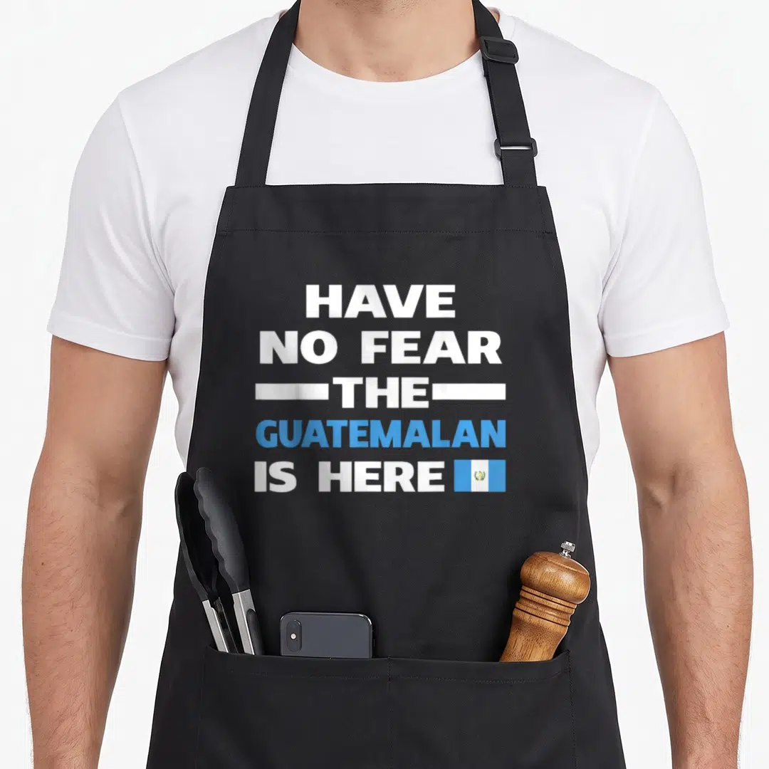 Proud guatemalan aprons - Stacked white and blue text reading Have No Fear The Guatemalan Is Here next to a small flag — shown on a black cotton canvas apron against a white background