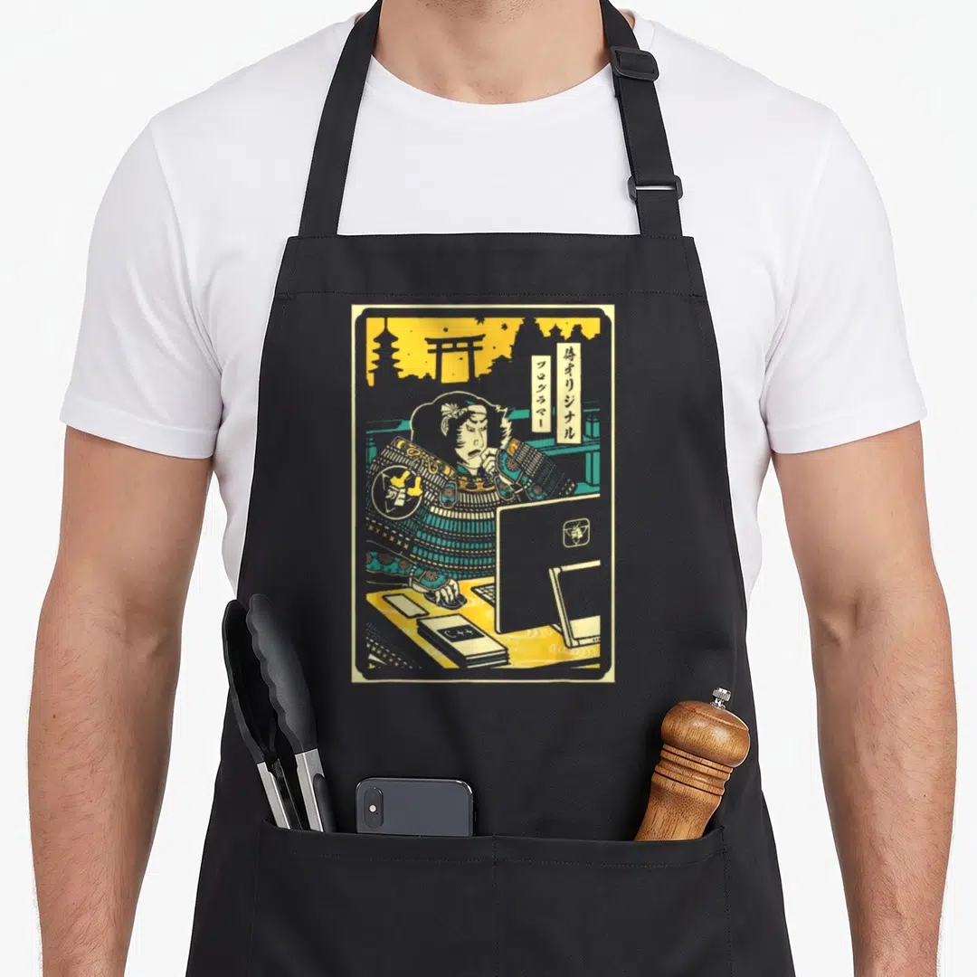 Samurai electronics apron - Cartoon samurai coding with Japanese text and C++ book on teal yellow background — shown on a black cotton canvas apron against a white background