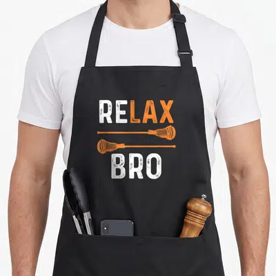 Relax sports team aprons - Distressed RELAX BRO text with two horizontal orange lacrosse sticks — shown on a black cotton canvas apron against a white background