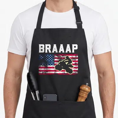 Quadrider atv apron - BRAAAP text over distressed flag with beige motocross rider silhouette in red blue and white — shown on a black cotton canvas apron against a white background