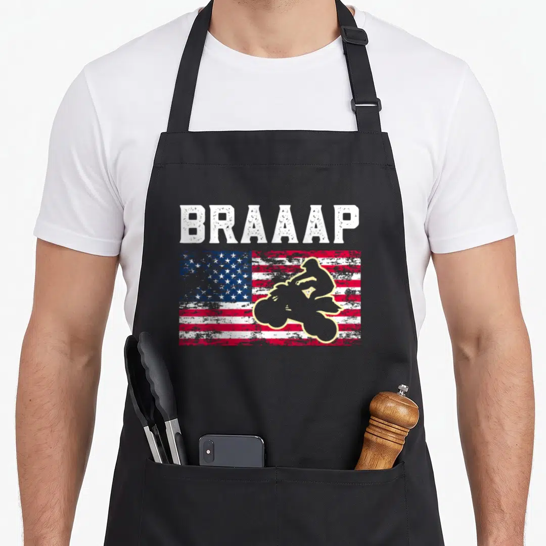 Quadrider atv apron - BRAAAP text over distressed flag with beige motocross rider silhouette in red blue and white — shown on a black cotton canvas apron against a white background