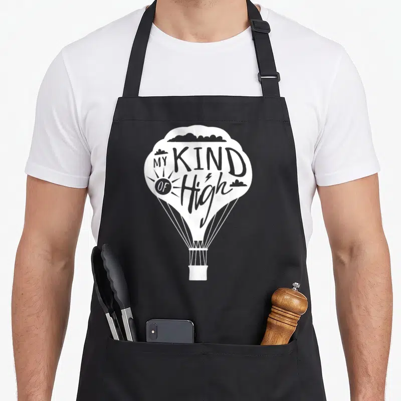 Kind balloon apron - White hot air balloon with MY KIND OF High text and lightning bolt inside the H — shown on a black cotton canvas apron against a white background