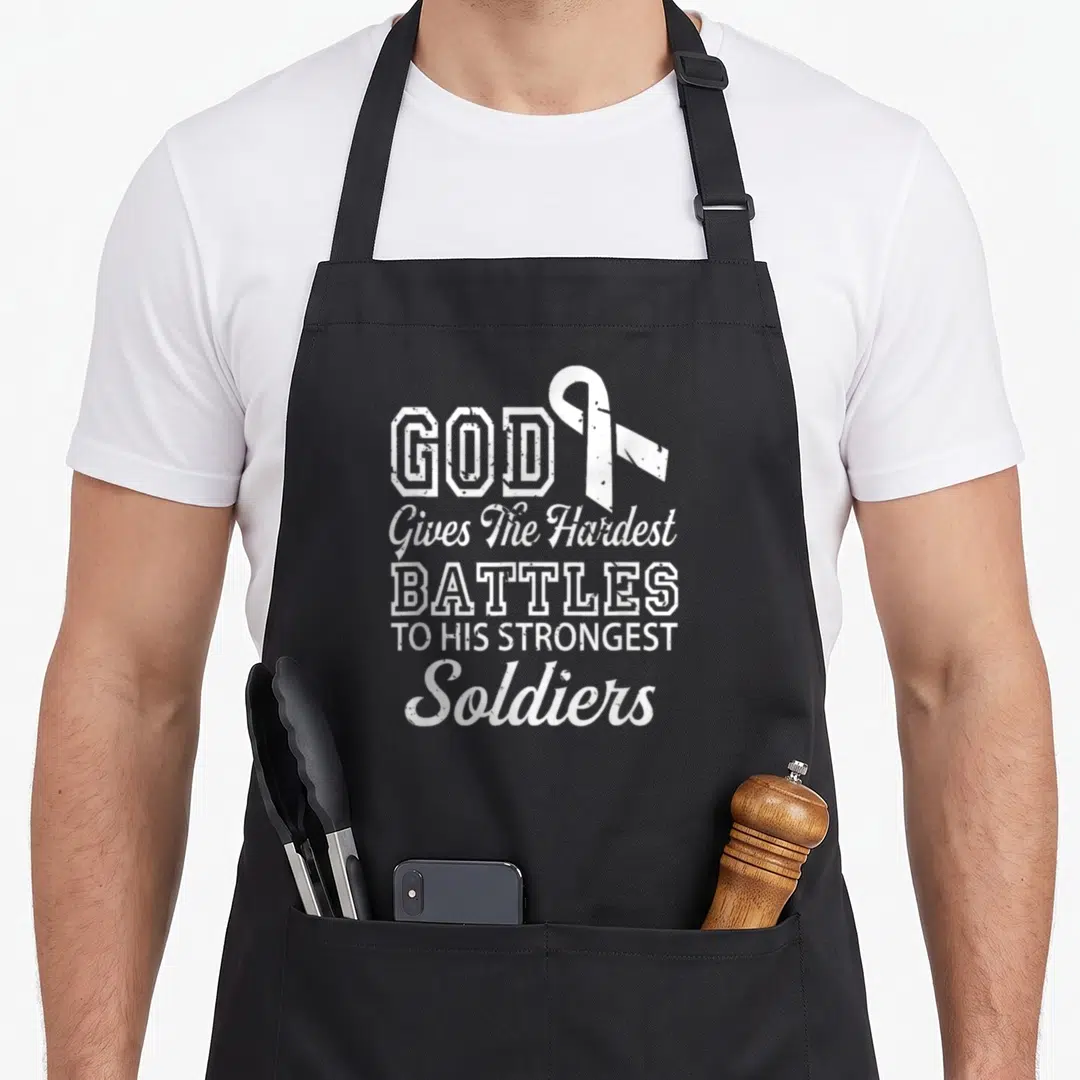 Lung prayer apron - White distressed text reading GOD Gives The Hardest Battles To His Strongest Soldiers beside — shown on a black cotton canvas apron against a white background