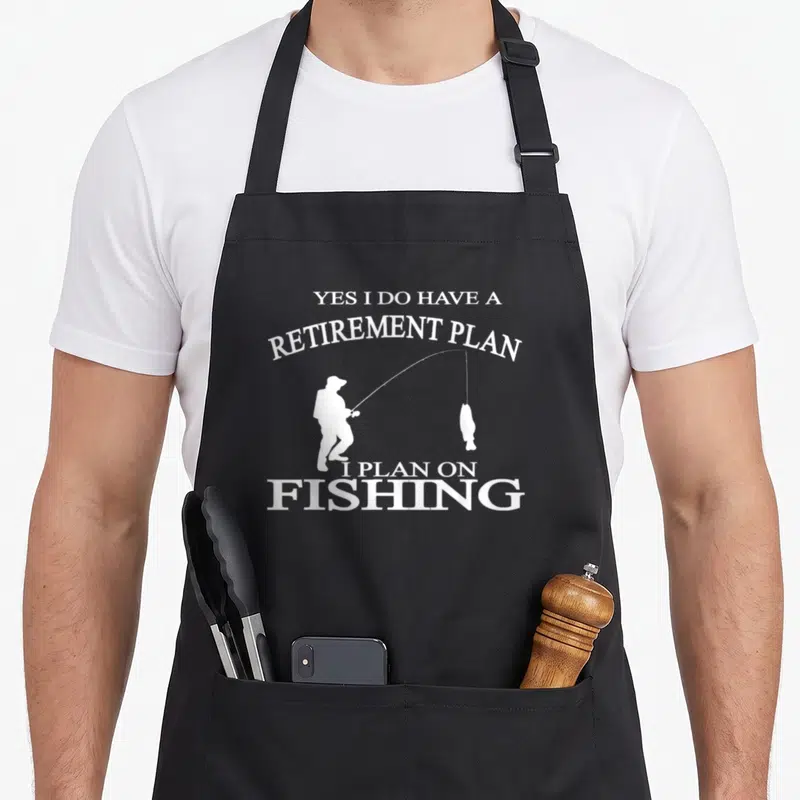 Retired fisherman apron - White fisherman silhouette holding rod with hanging fish surrounded by retirement plan — shown on a black cotton canvas apron against a white background