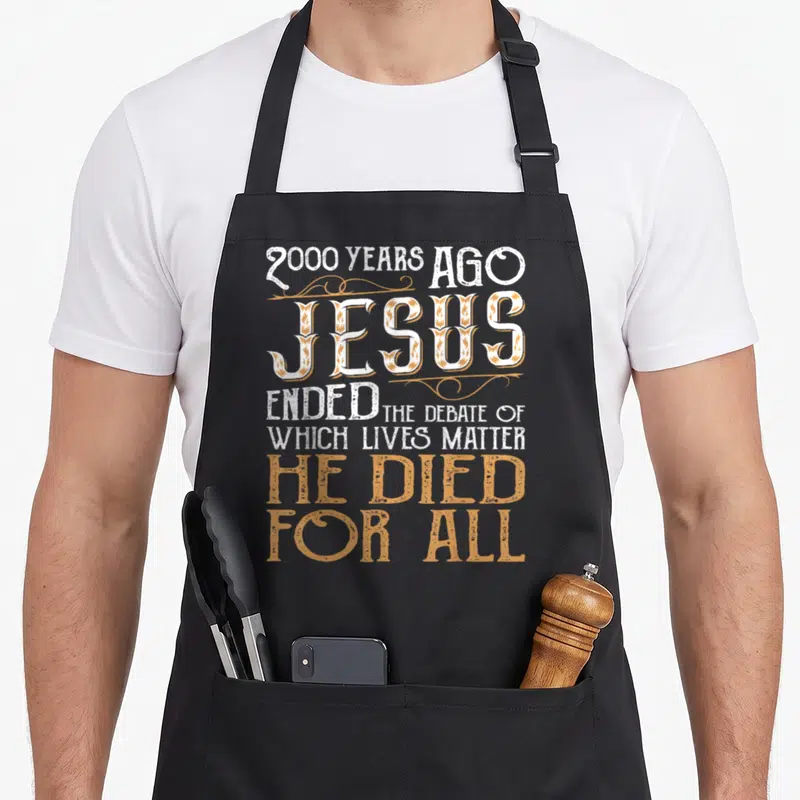 Debate christian apron - Gold and white typography art reading 2000 years ago Jesus ended the debate of which lives — shown on a black cotton canvas apron against a white background