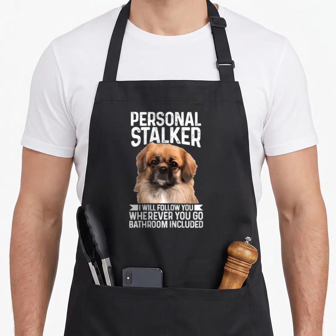 Pekingese personal chef apron - Cartoon Pekingese dog with Personal Stalker text and bathroom included quote — shown on a black cotton canvas apron against a white background