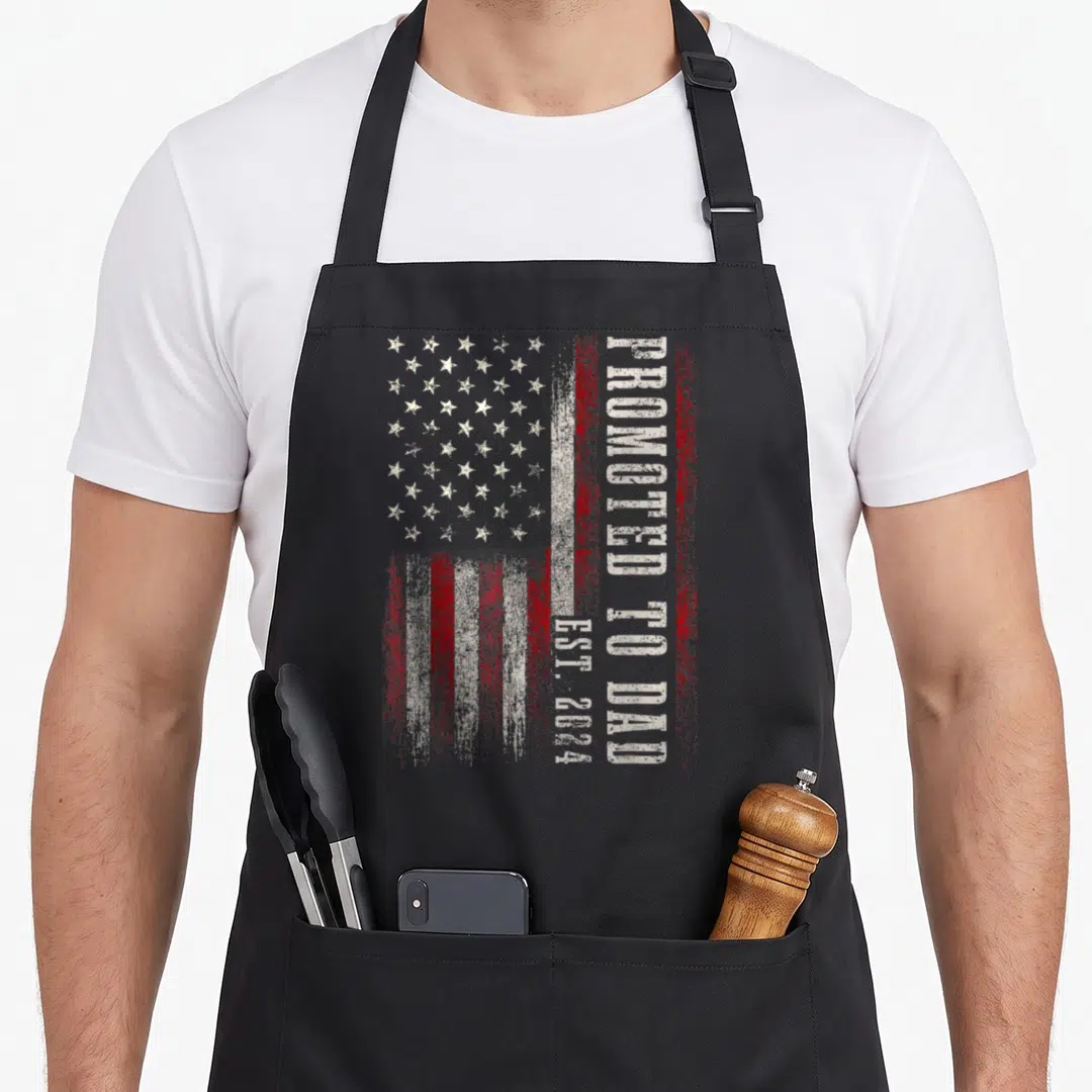 Expect father day apron - Distressed USA flag with vertical Promoted to Dad Est 2024 text in red and white — shown on a black cotton canvas apron against a white background
