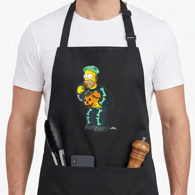 Homer halloween apron - Homer Simpson standing in skeleton costume holding pumpkin bucket and eating candy — shown on a black cotton canvas apron against a white background