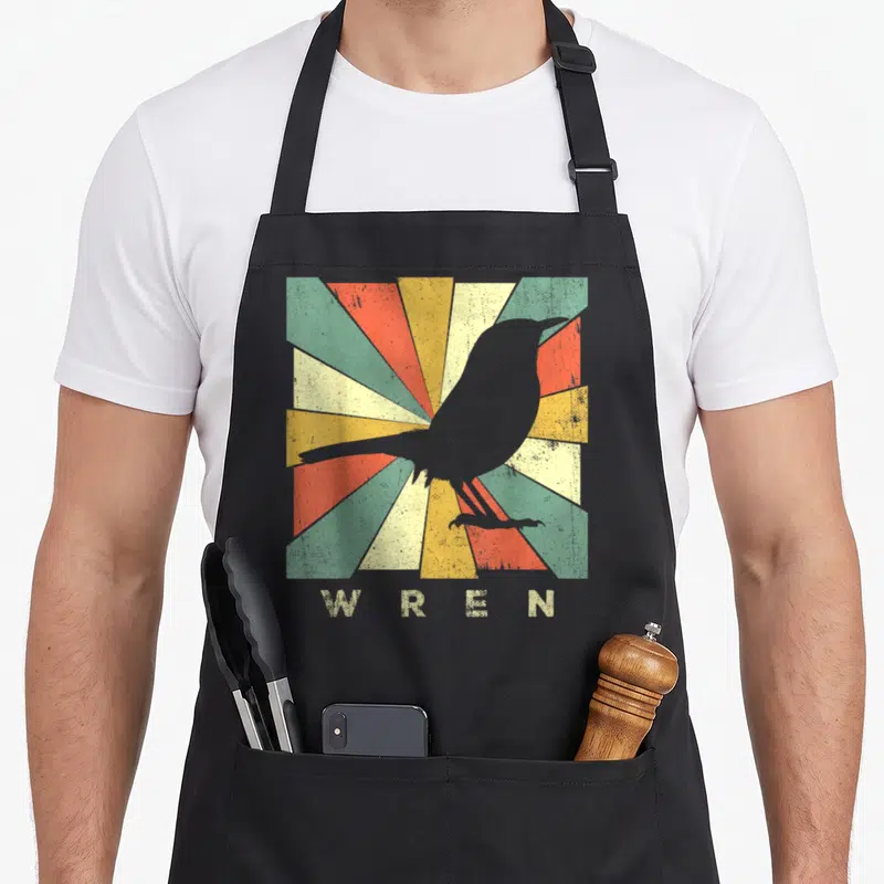 Wren birds apron - Grey wren silhouette over multicolored sunburst rays with WREN text below — shown on a black cotton canvas apron against a white background