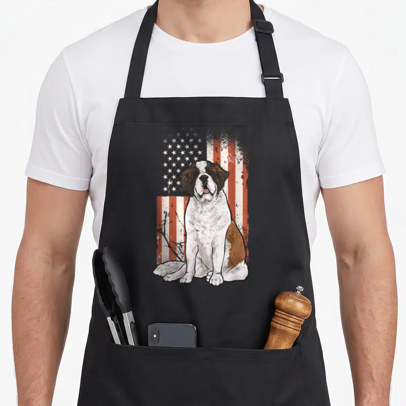 Bernard american flag apron - Seated Saint Bernard dog illustration overlaid on a distressed red white and blue USA flag — shown on a black cotton canvas apron against a white background