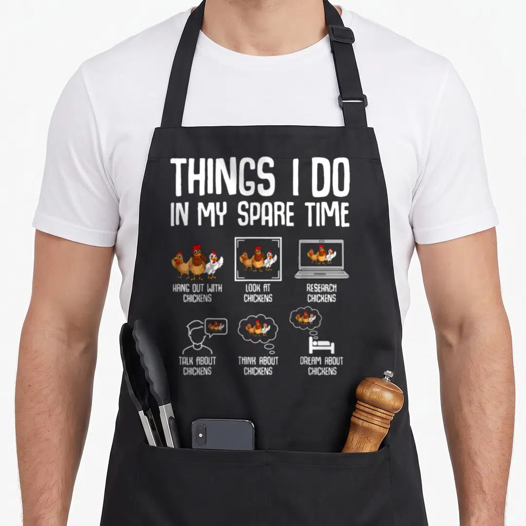 Funny spare chicken apron - Cartoon chickens standing and on laptop with text Things I Do In My Spare Time — shown on a black cotton canvas apron against a white background