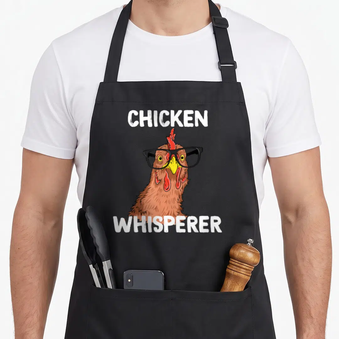 Chicken farm apron - Cartoon brown chicken wearing black glasses between white text — shown on a black cotton canvas apron against a white background
