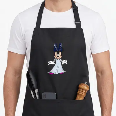 Retro halloween mummy and me aprons - Cartoon Minnie Mouse in grey mummy gown with blue bow and pink shoes — shown on a black cotton canvas apron against a white background