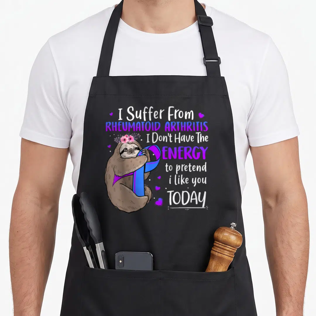 Rheumatoid sloth apron - Cartoon sloth holding purple blue ribbon with I Suffer From Rheumatoid Arthritis text — shown on a black cotton canvas apron against a white background