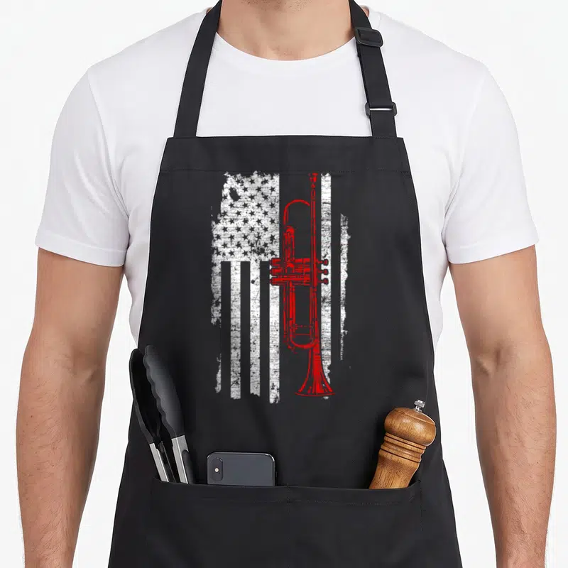 Jazz line apron - Red trumpet superimposed over distressed white USA flag pattern — shown on a black cotton canvas apron against a white background