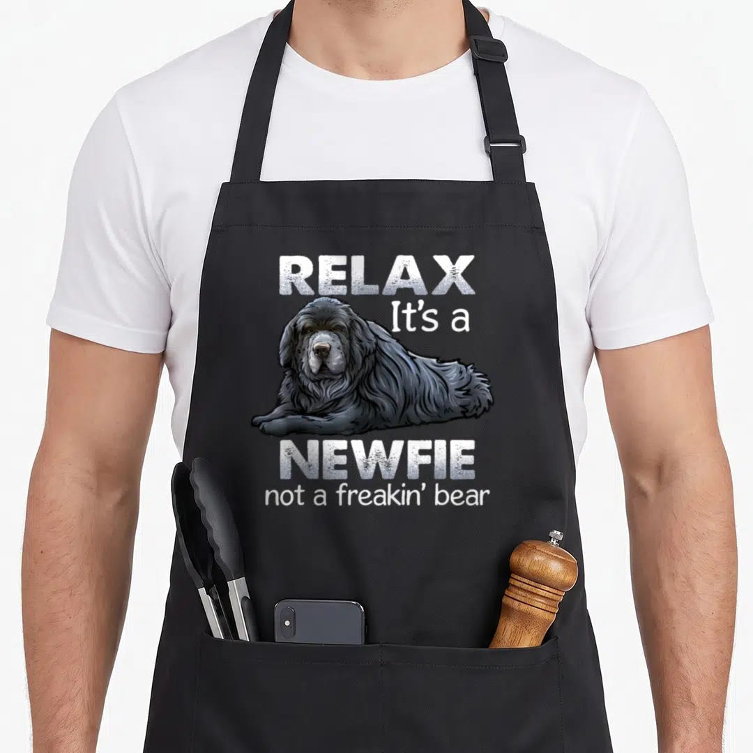 Critterz christmas dog apron - Realistic black newfoundland dog with white text relax its a newfie not a freakin bear — shown on a black cotton canvas apron against a white background