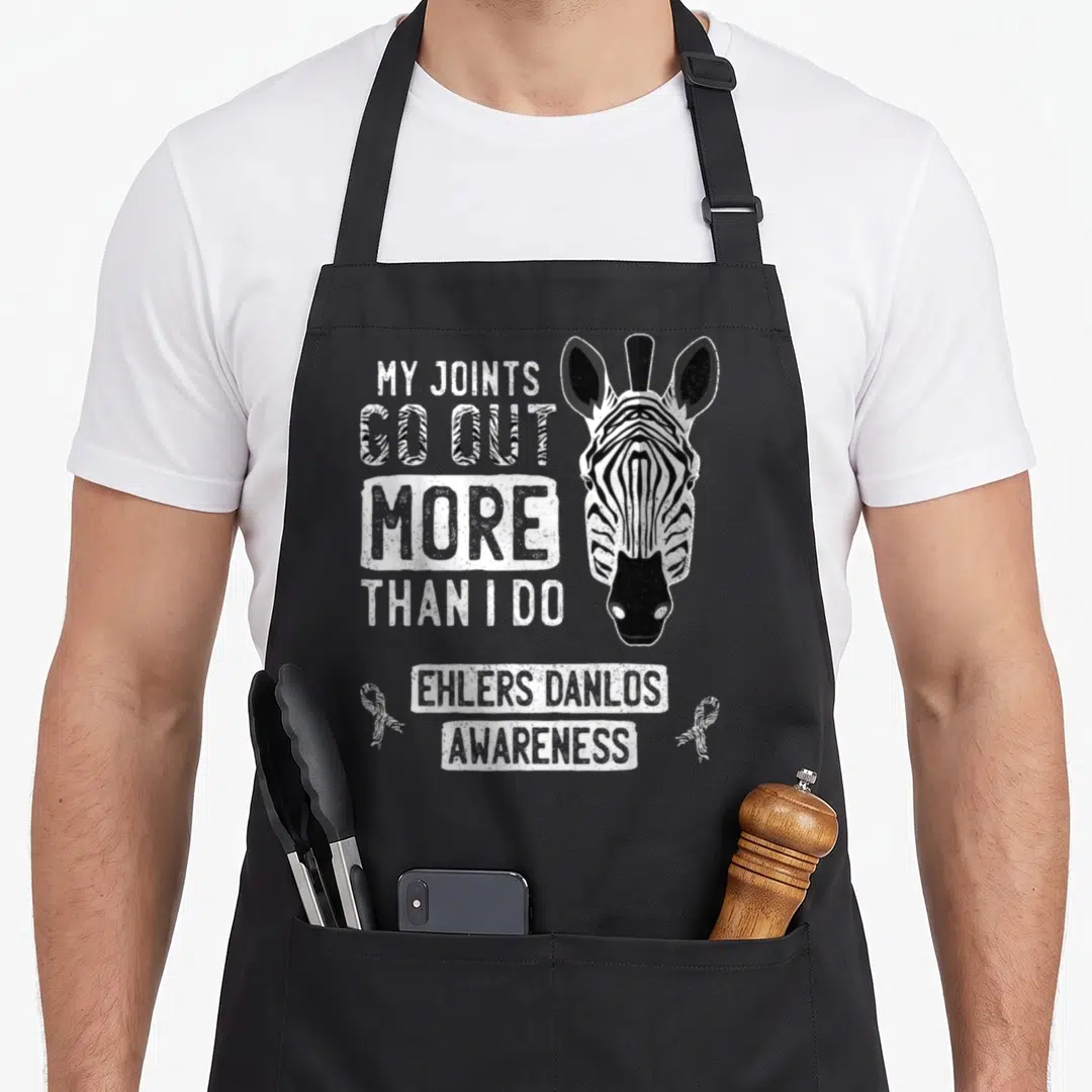 Joint zebra apron - Zebra head and My Joints Go Out text with striped awareness ribbons — shown on a black cotton canvas apron against a white background