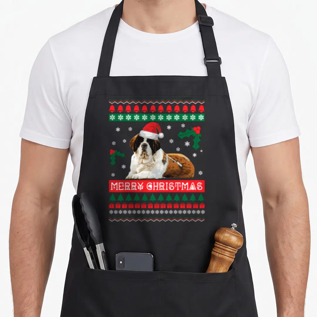 Bernard ugly christmas sweater apron - Saint Bernard wearing Santa hat surrounded by bells snowflakes trees and MERRY — shown on a black cotton canvas apron against a white background