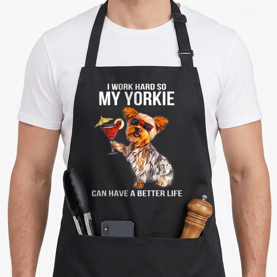 Hard yorkshire apron - Cartoon Yorkie with sunglasses holding red cocktail, white text on black bib — shown on a black cotton canvas apron against a white background