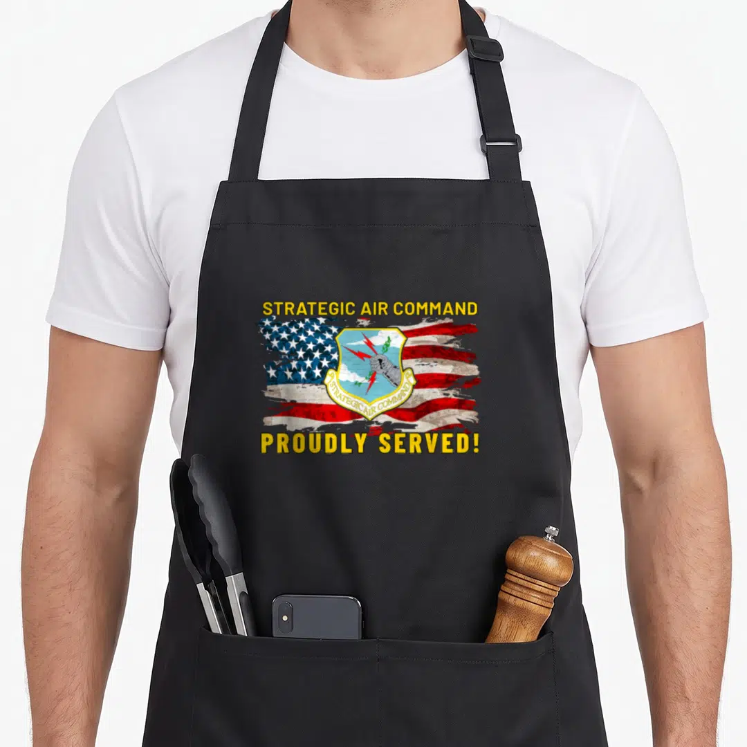Strategic us aprons - Distressed flag with SAC emblem and yellow text PROUDLY SERVED — shown on a black cotton canvas apron against a white background
