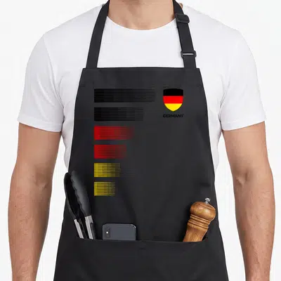 Emblem patriotic apron - Shield with GERMANY text and six groups of black, red, and yellow horizontal lines — shown on a black cotton canvas apron against a white background