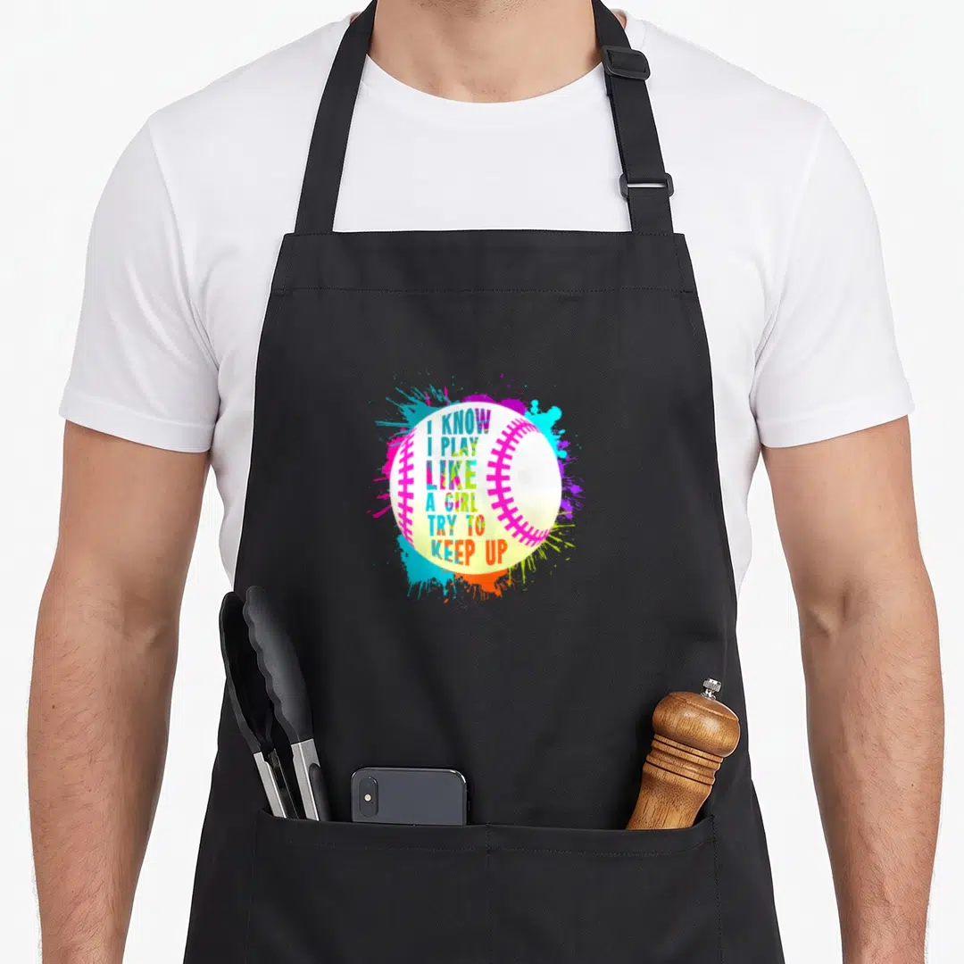 Play softball baseball apron - White baseball with pink stitching and colorful text I KNOW I PLAY LIKE A GIRL TRY — shown on a black cotton canvas apron against a white background