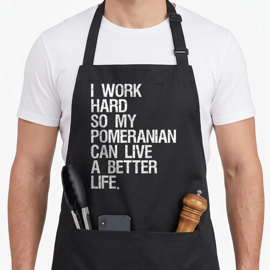 Hard along life apron - White distressed text reading I WORK HARD SO MY POMERANIAN CAN LIVE A BETTER LIFE stacked — shown on a black cotton canvas apron against a white background