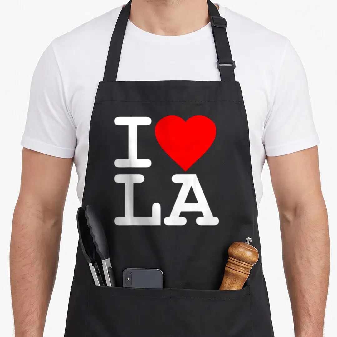 Flippin gear apron - White I and LA letters with a red heart symbol arranged vertically — shown on a black cotton canvas apron against a white background