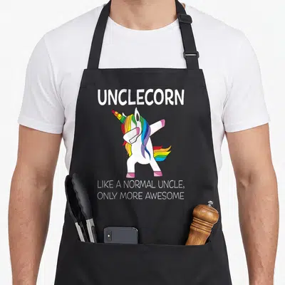 Uncle unicorn apron - White cartoon unicorn dabbing with rainbow mane and text Unclecorn Like a Normal Uncle Only More — shown on a black cotton canvas apron against a white background