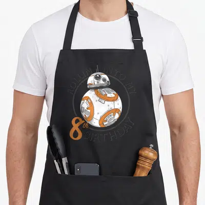 Portrait birthday apron - BB-8 droid in grey circle with rollin into my 8th birthday text — shown on a black cotton canvas apron against a white background