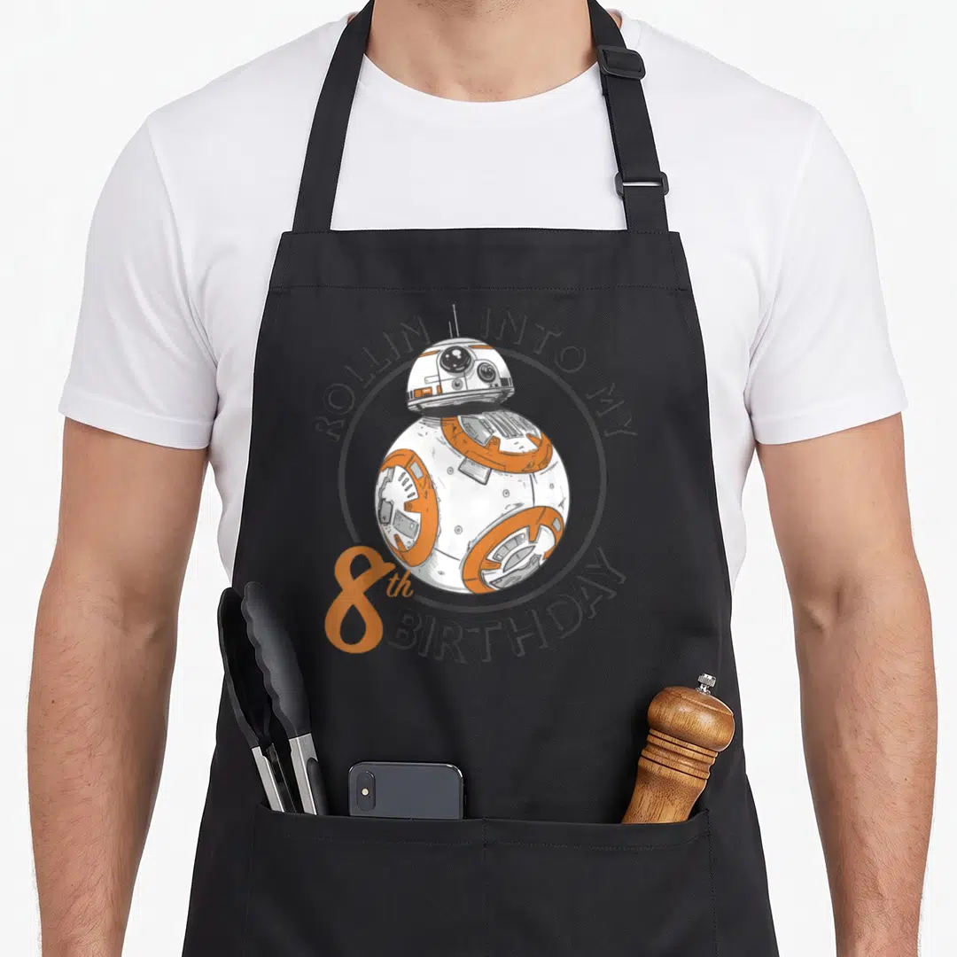 Portrait birthday apron - BB-8 droid in grey circle with rollin into my 8th birthday text — shown on a black cotton canvas apron against a white background