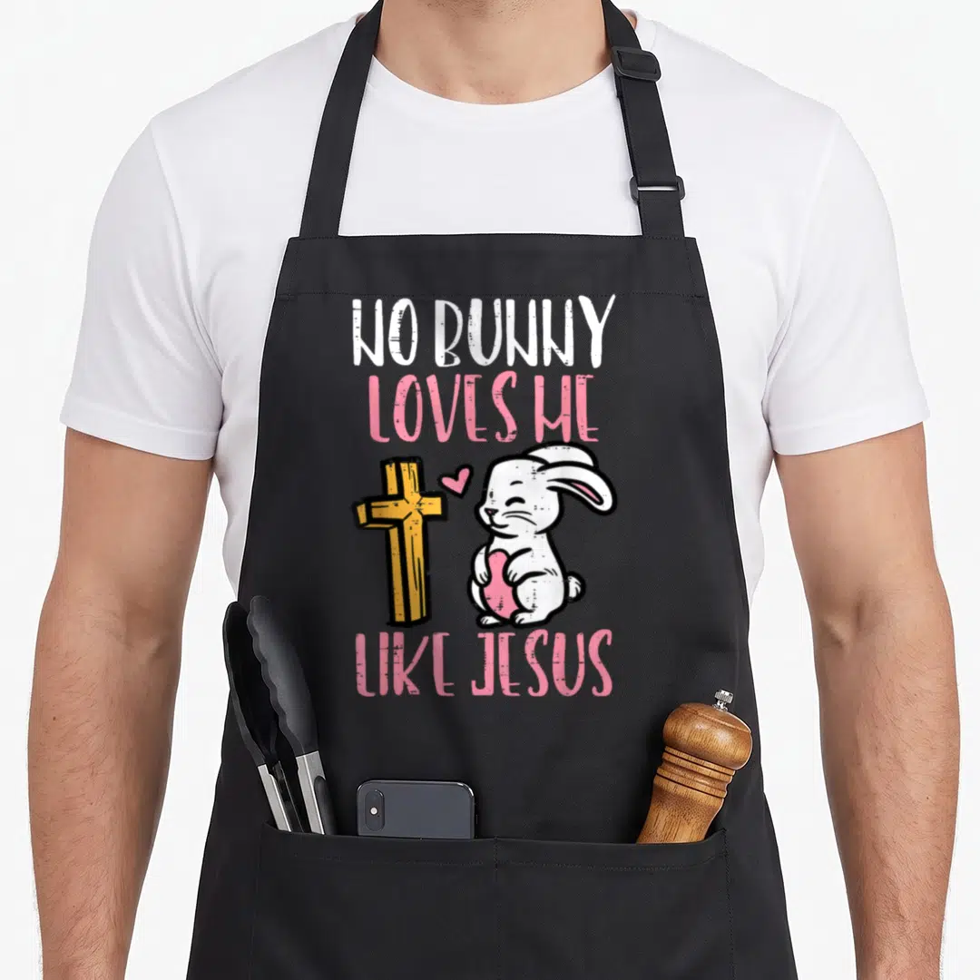 Bunny jesus easter apron - Cartoon white bunny holding pink heart beside yellow cross with NO BUNNY LOVES ME LIKE JESUS — shown on a black cotton canvas apron against a white background