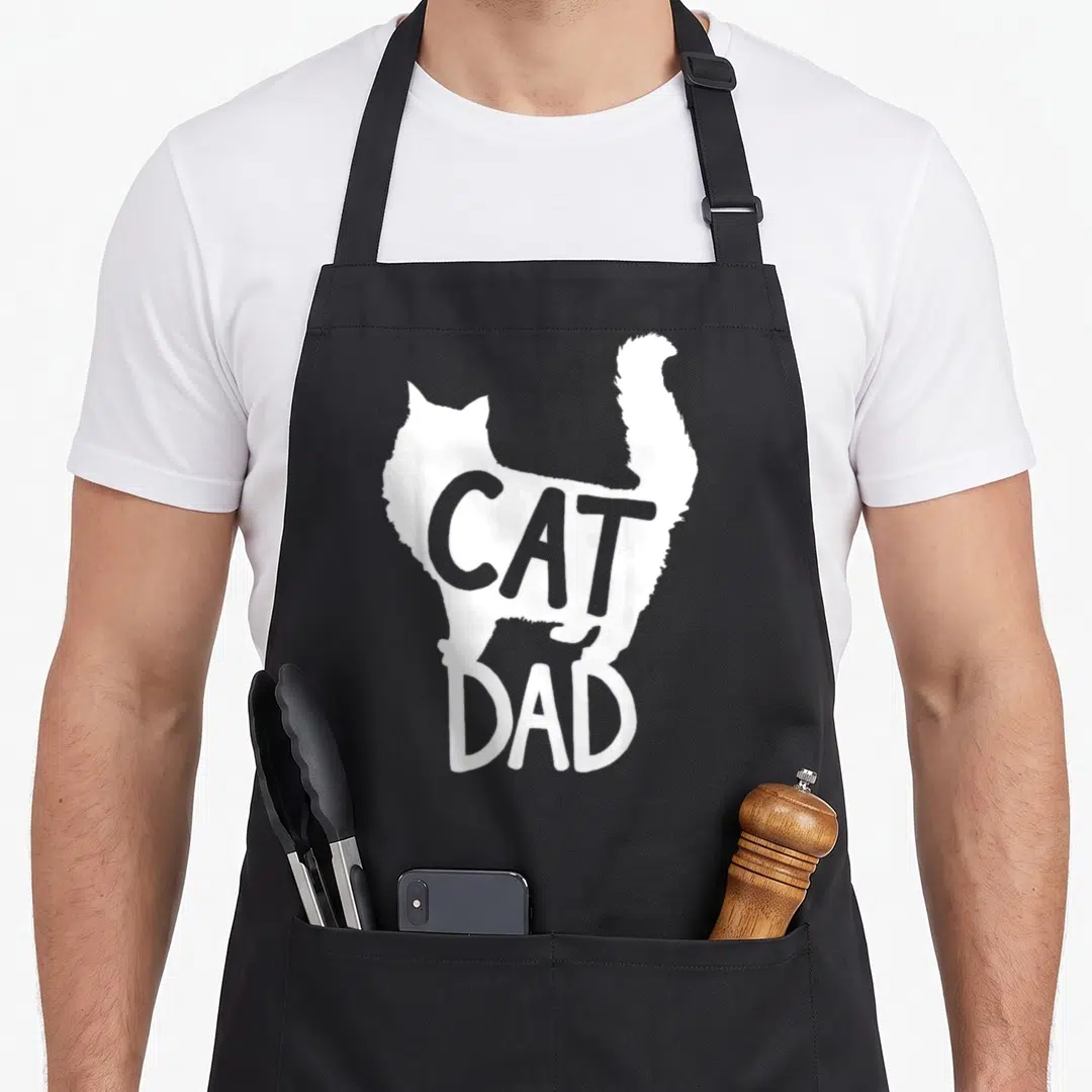 Father grill daddy apron - White cat silhouette with grey CAT and white DAD text on black background — shown on a black cotton canvas apron against a white background