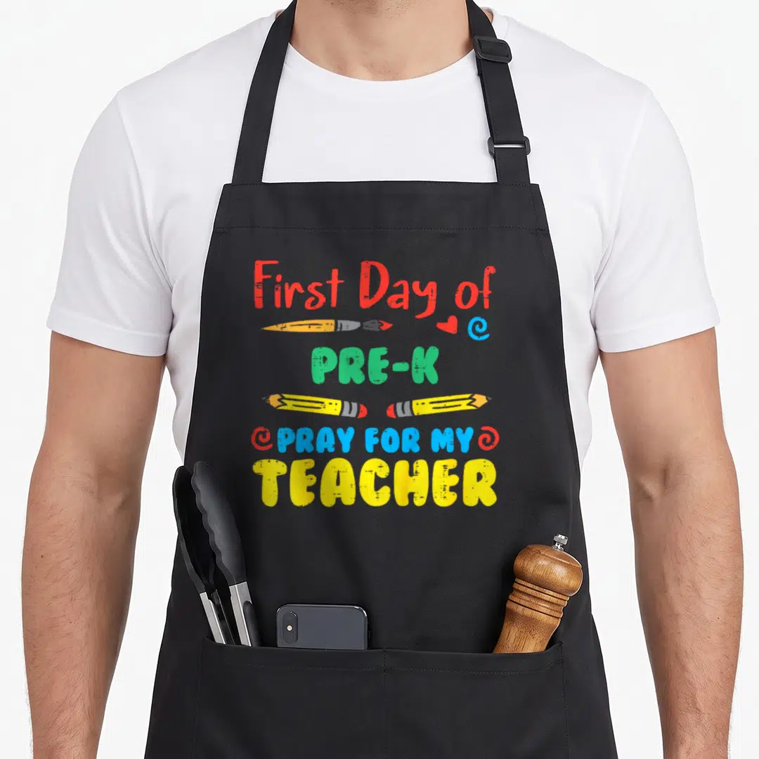 Pray day pre k apron - Stacked text First Day Pre-K Pray For My Teacher with colored pencils and heart icons — shown on a black cotton canvas apron against a white background