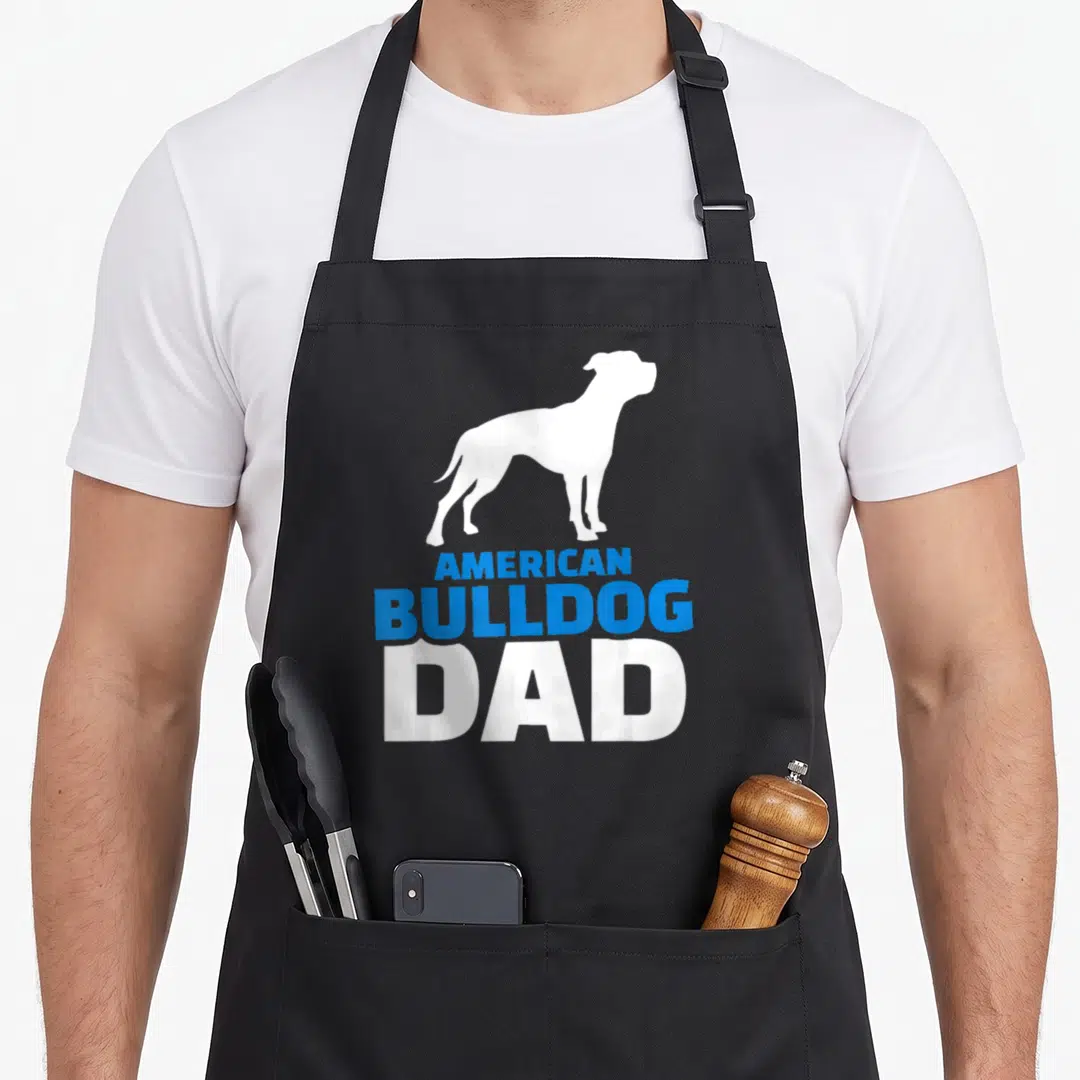 Bulldog english dad apron - White dog silhouette above stacked blue and white text reading American Bulldog Dad — shown on a black cotton canvas apron against a white background