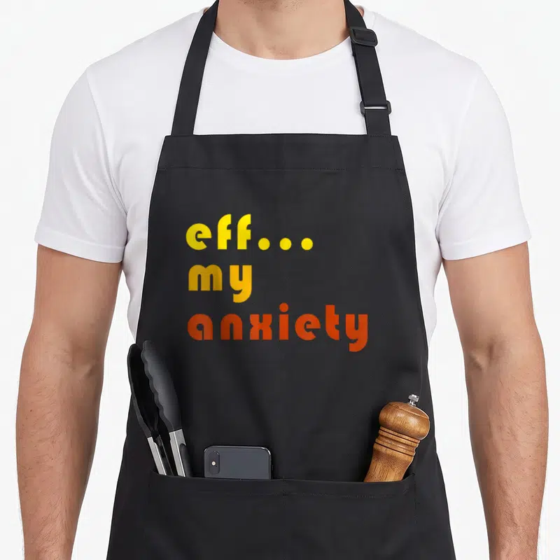 Eff anxiety awareness apron - Stacked eff my anxiety text in yellow and orange gradient font — shown on a black cotton canvas apron against a white background