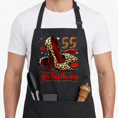Fabulous heel birthday apron - Leopard print high heels with 55 and Fabulous text and red lips — shown on a black cotton canvas apron against a white background