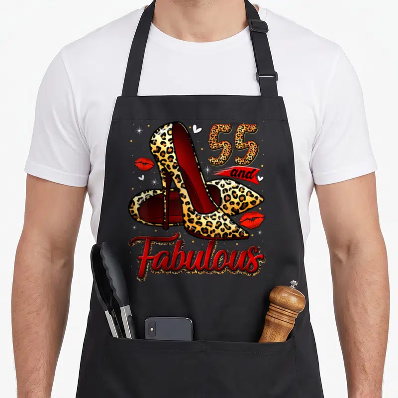 Fabulous heel birthday apron - Leopard print high heels with 55 and Fabulous text and red lips — shown on a black cotton canvas apron against a white background