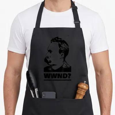 Philosophy x apron - Black and white man's head profile above underlined WWND? text — shown on a black cotton canvas apron against a white background