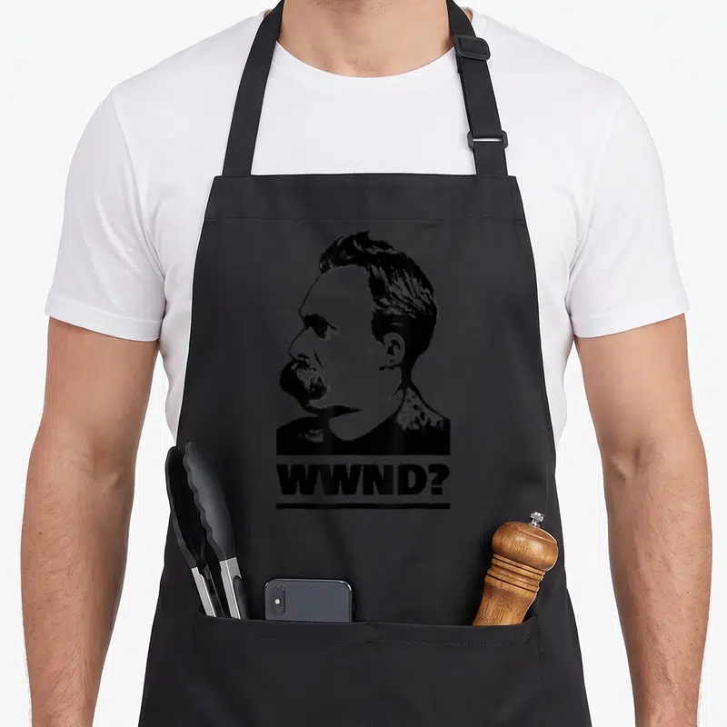 Philosophy x apron - Black and white man's head profile above underlined WWND? text — shown on a black cotton canvas apron against a white background