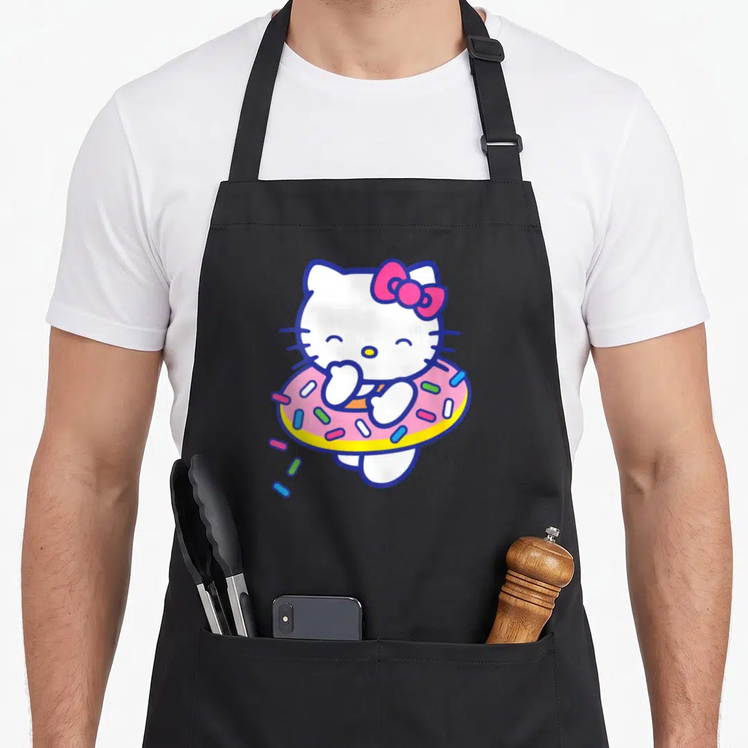 Floaty sprinkle apron - Hello Kitty standing in pink donut with blue yellow sprinkles and pink bow — shown on a black cotton canvas apron against a white background