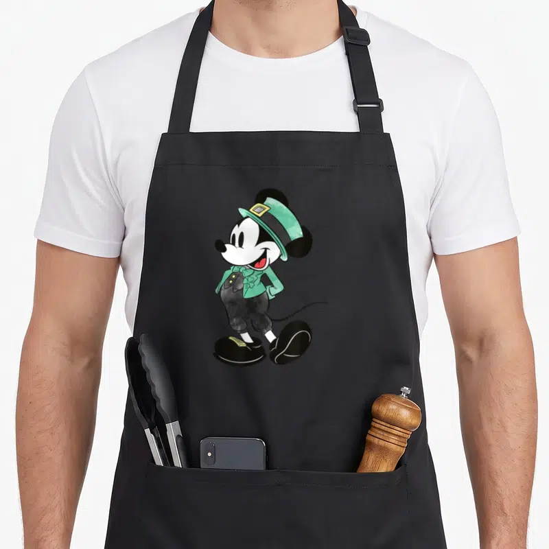 Costume irish aprons - Watercolor Mickey Mouse in green leprechaun hat and jacket with shamrock detail — shown on a black cotton canvas apron against a white background