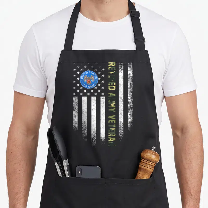Retired army american flag apron - Distressed white flag with US Army seal and vertical olive tan text reading RETIRED — shown on a black cotton canvas apron against a white background