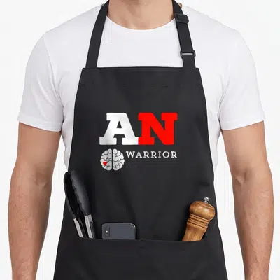 Warrior acoustics apron - AN WARRIOR text above white brain with red heart icon — shown on a black cotton canvas apron against a white background