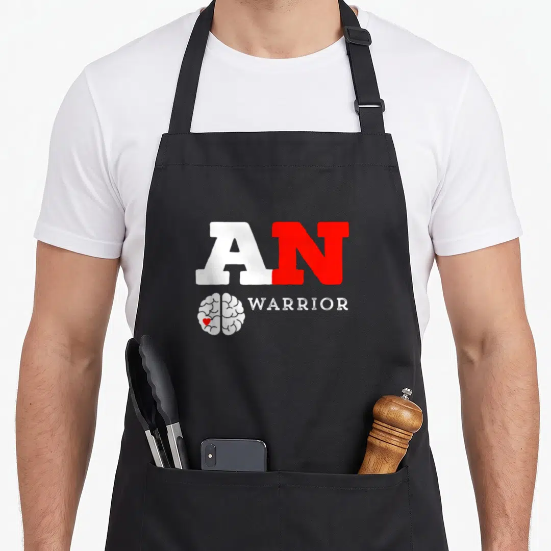 Warrior acoustics apron - AN WARRIOR text above white brain with red heart icon — shown on a black cotton canvas apron against a white background