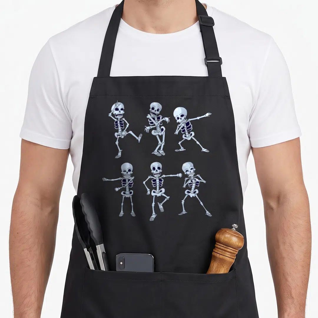 Dancing skeleton apron - Six light blue and white cartoon skeletons in various dance poses on a black background — shown on a black cotton canvas apron against a white background