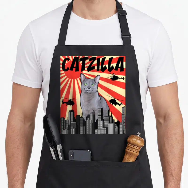 Japanese russian aprons - Giant grey cat CATZILLA behind city skyline with helicopters on red sunburst background — shown on a black cotton canvas apron against a white background
