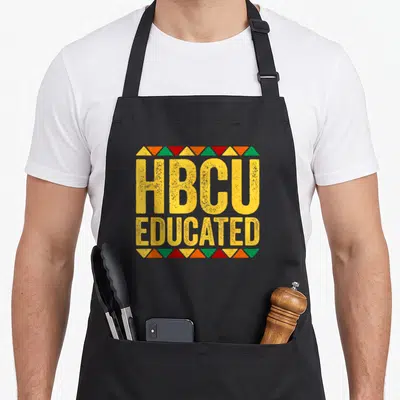 Educated historical aprons - Distressed yellow HBCU EDUCATED text framed by red green orange triangles — shown on a black cotton canvas apron against a white background