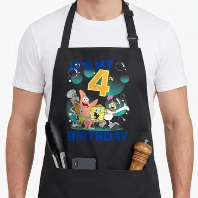 Squarepant 4th birthday apron - Cartoon characters with IT'S MY 4TH BIRTHDAY text and bubbles in blue yellow pink green — shown on a black cotton canvas apron against a white background