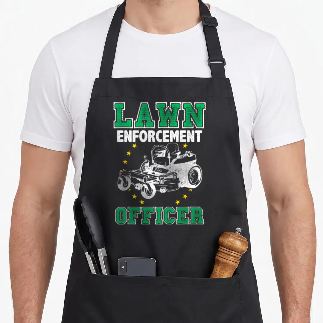 Enforcement rangers apron - LAWN ENFORCEMENT OFFICER text with white riding mower and yellow stars in distressed print — shown on a black cotton canvas apron against a white background